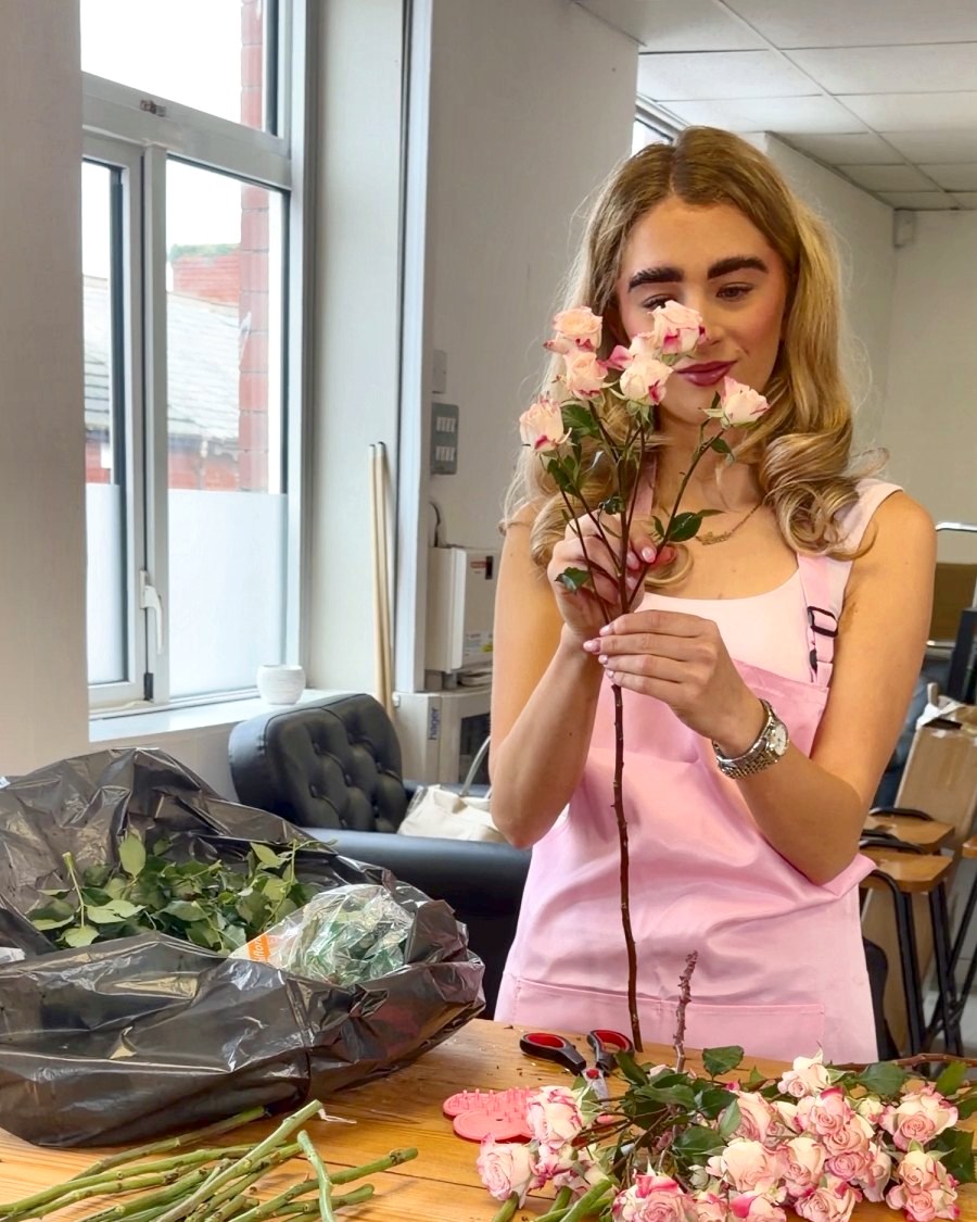 A student holding a pink rose at the flower table
