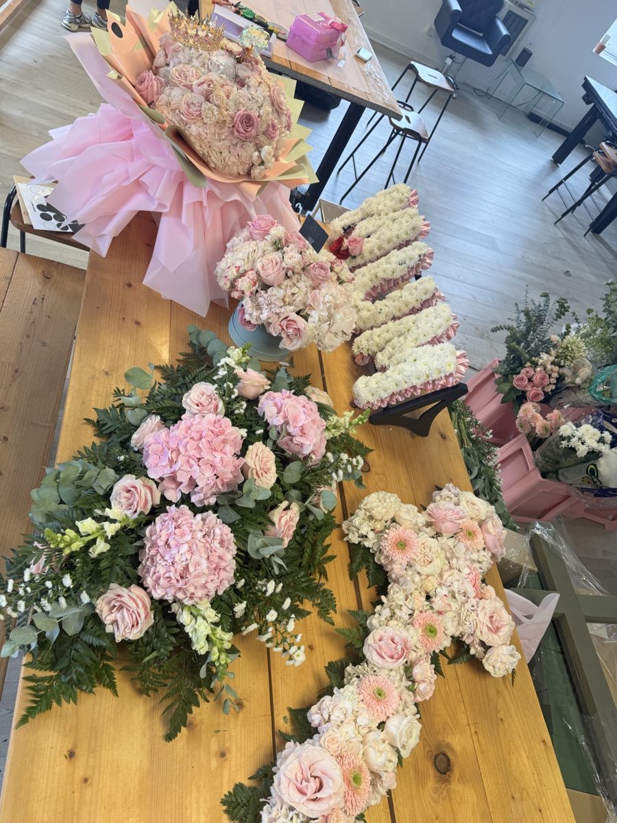 A pink hydrangea spray beside a floral cross and a letter tribute