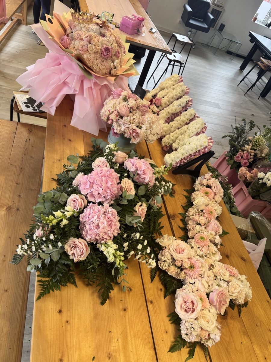 A hydrangea spray, a floral cross and a letter tribute laid out on the table