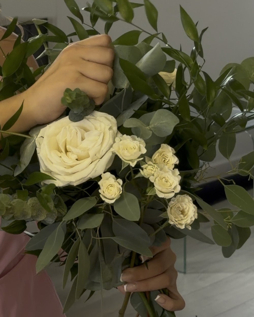 Holding a bridal bouquet of white roses, spray roses and eucalyptus