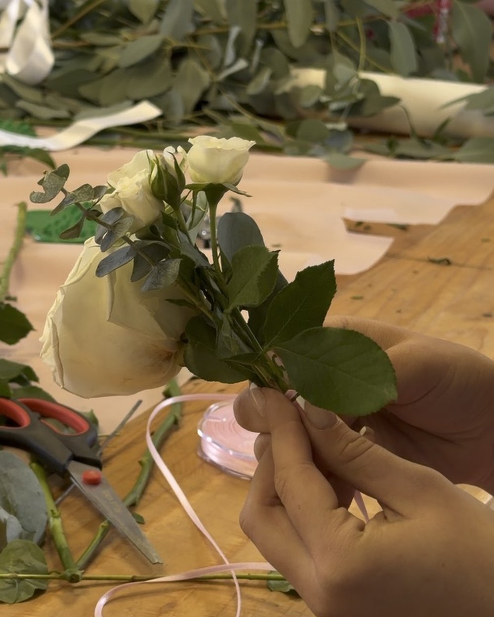 Making a small rose corsage with ribbon at the workshop table