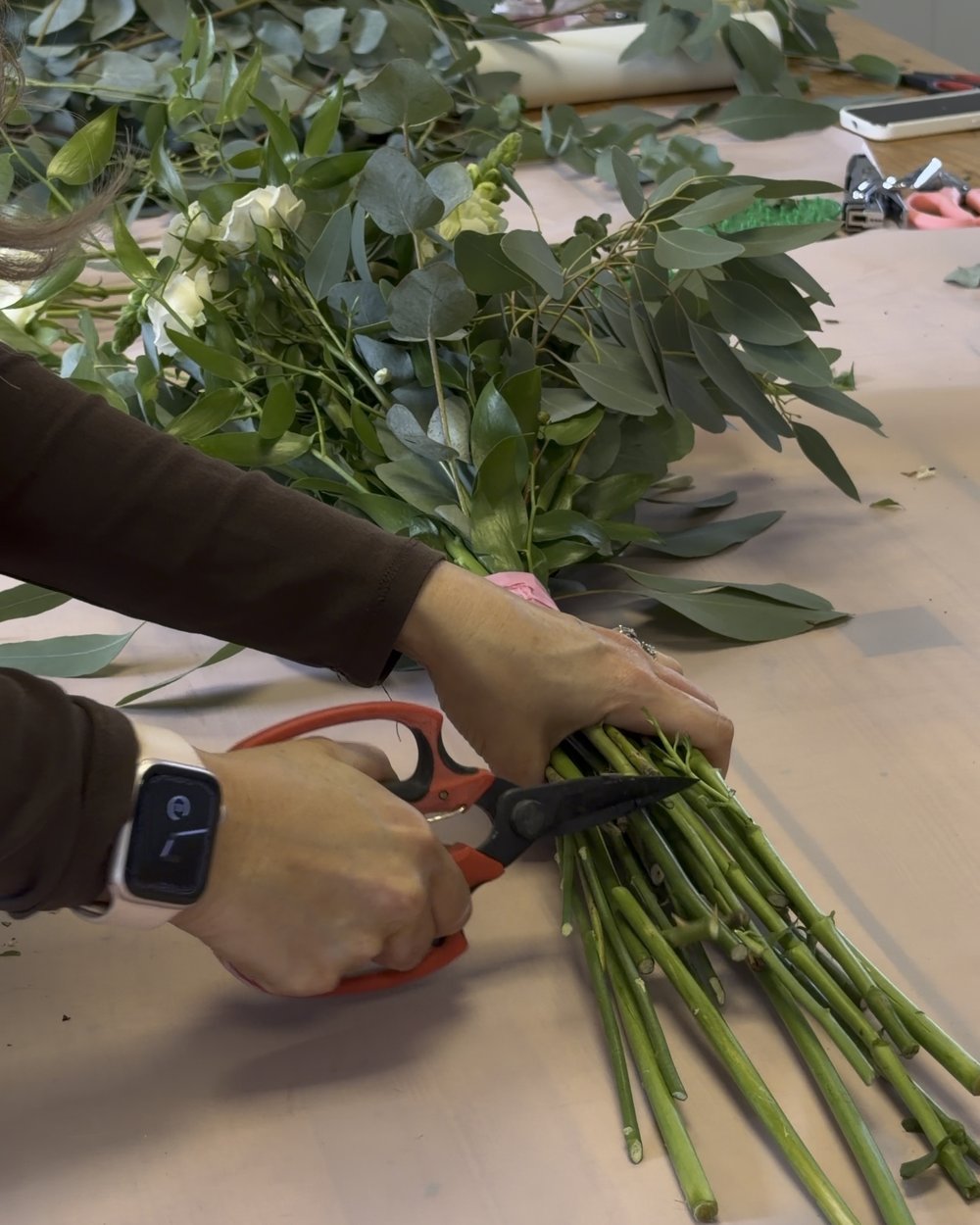 Cutting the stems of a hand-tied bouquet with florist scissors