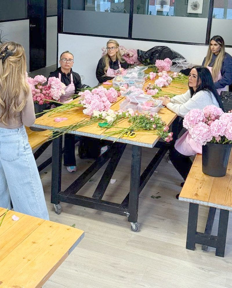 Everyone working around the tables of pink peonies and roses