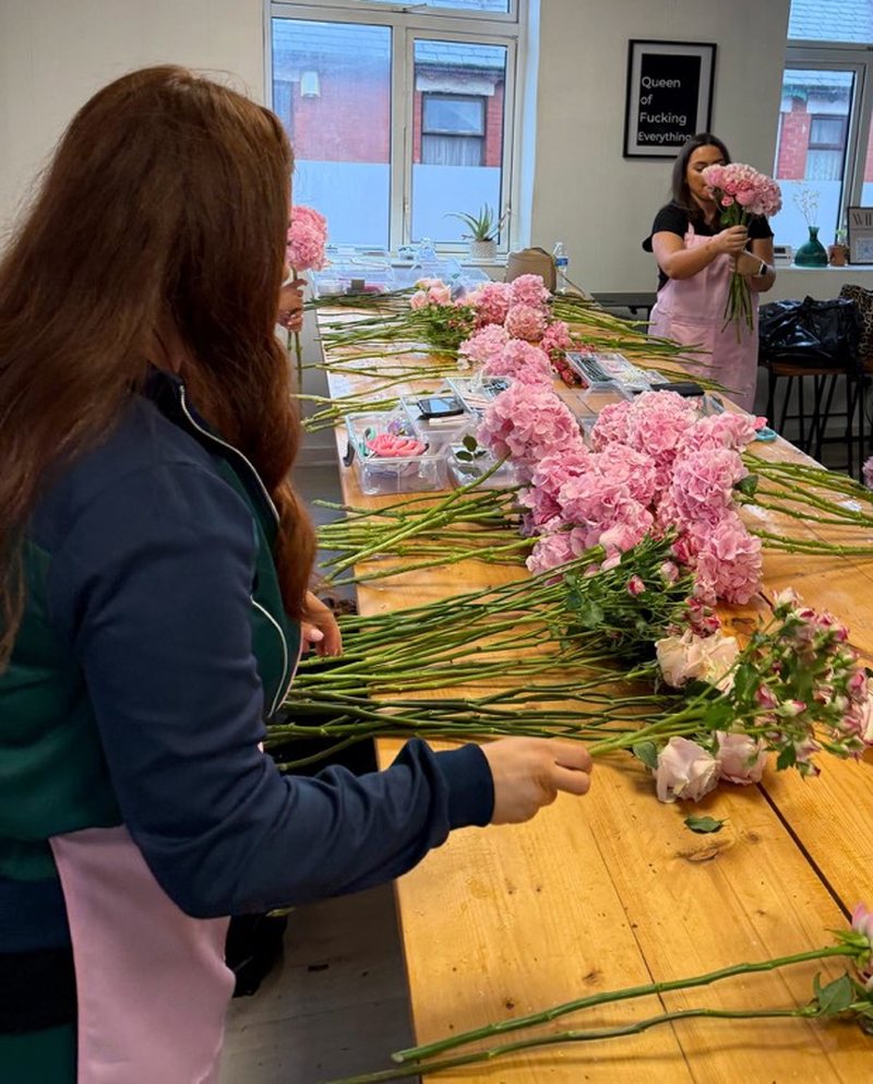 A student at a table full of pink hydrangeas and stems