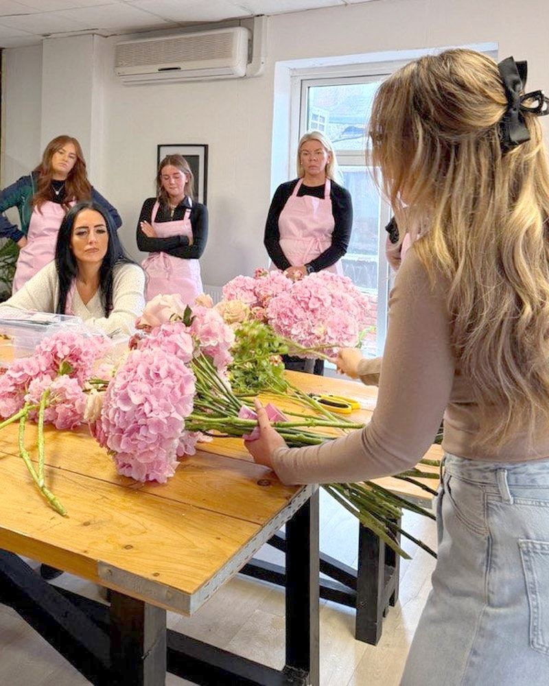 Making flowers together at a long table of pink stems