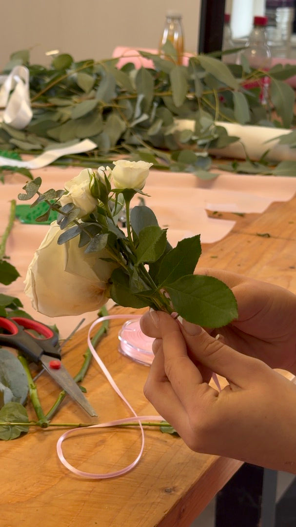 Tying a ribbon on a small rose corsage