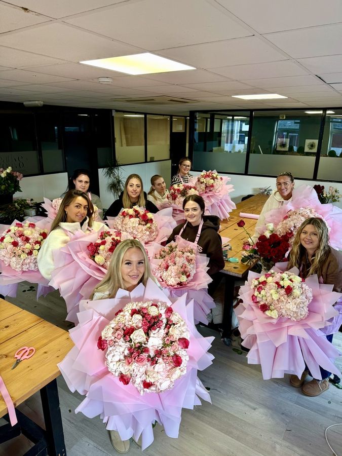 A class of students behind their red and pink bouquets
