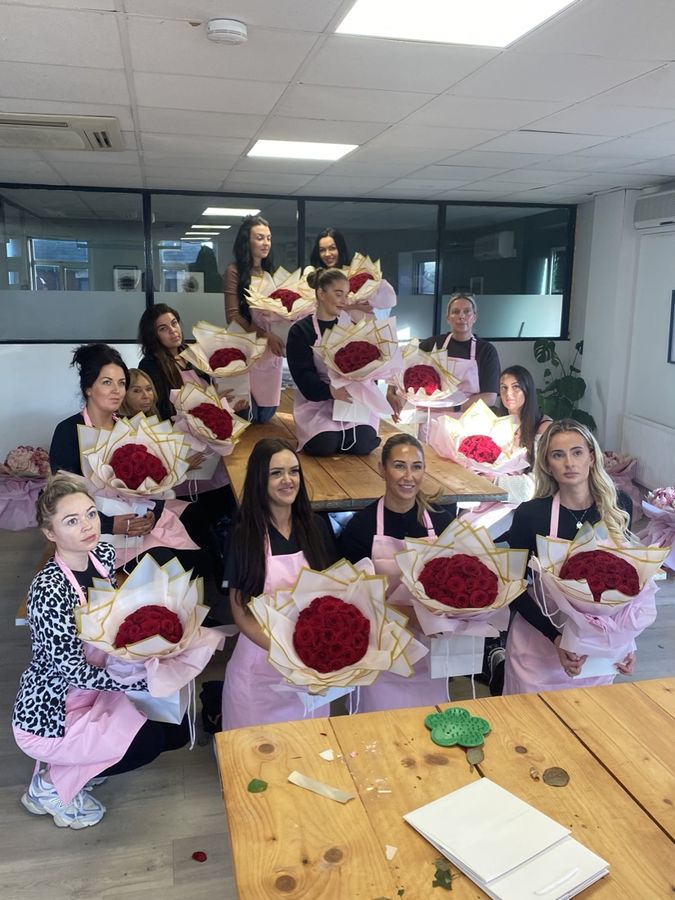 A large class with red rose bouquets on the table