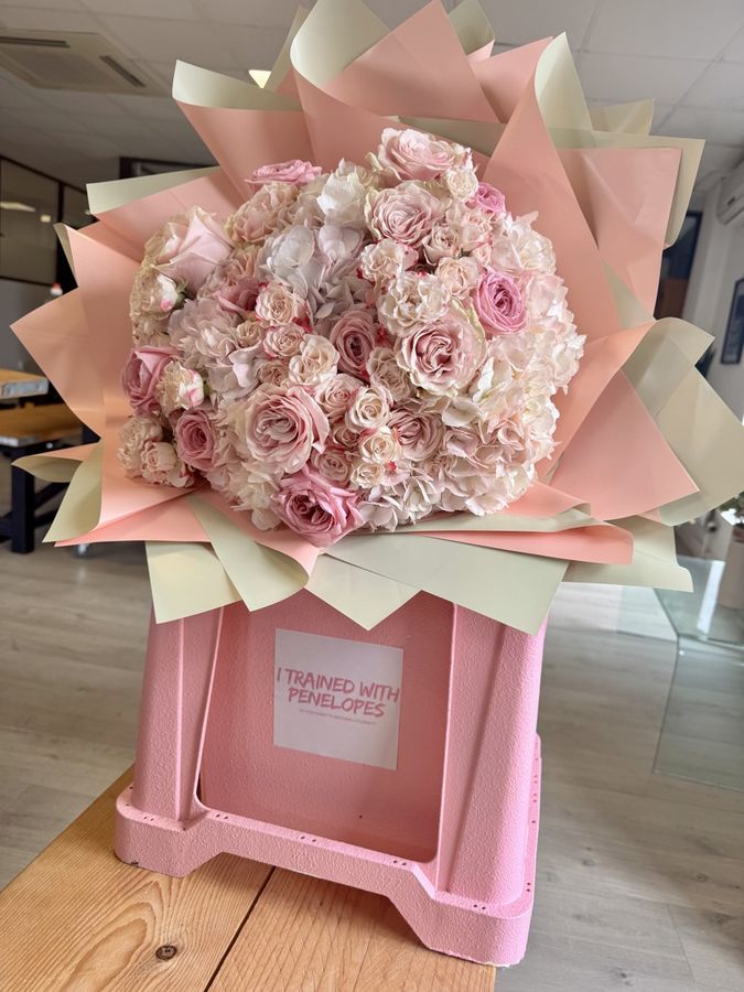 A large rose and hydrangea bouquet in a pink box