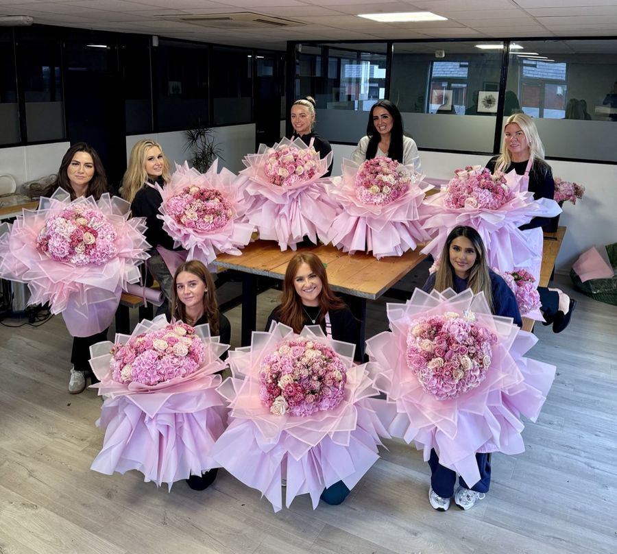 A group of students with their finished pink bouquets
