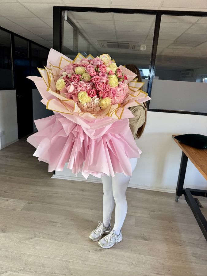 A student holding a finished bouquet in pink wrap