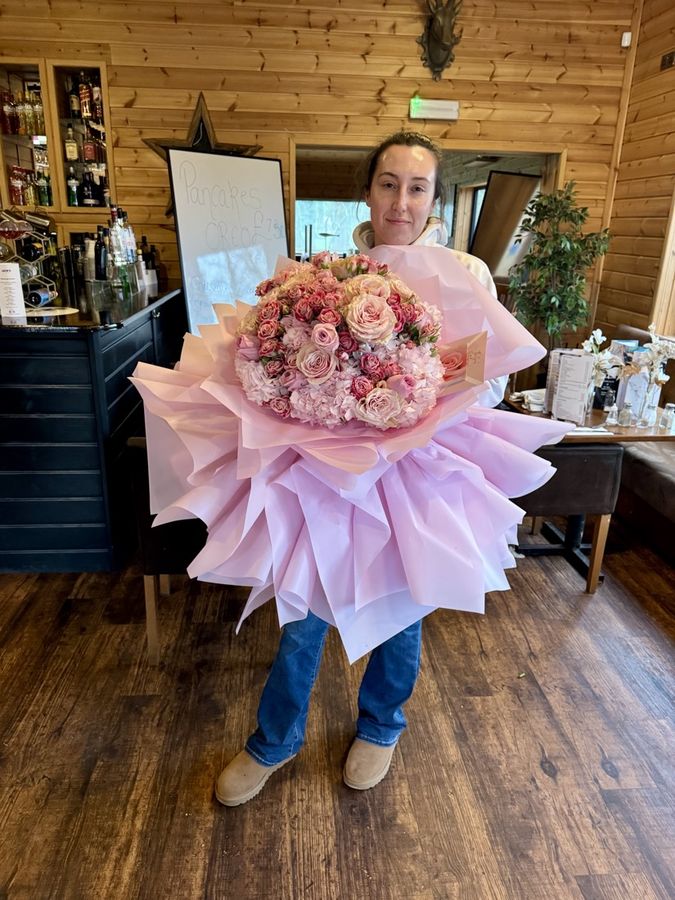 A student holding a huge bouquet of roses and hydrangeas
